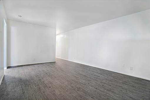 A room with wooden flooring and white walls.