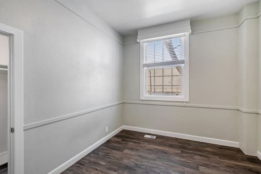 an empty room with wood flooring and a window