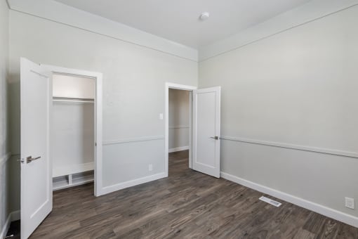 a bedroom with white walls and wood flooring and two doors