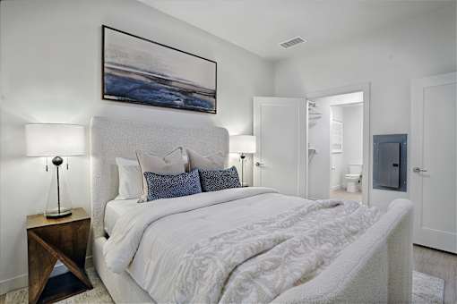 A bedroom with a large bed and a painting on the wall.
