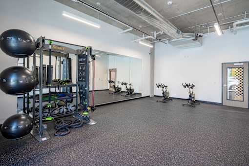 A gym with a variety of equipment including a squat rack, kettlebells, and a mirror.