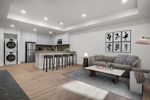 A modern kitchen with a bar area and a living room with a grey sofa.