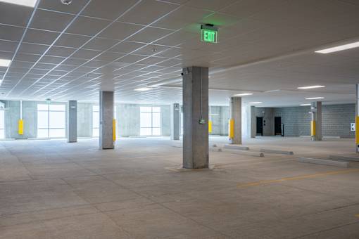 A large, empty parking garage with a green exit sign.