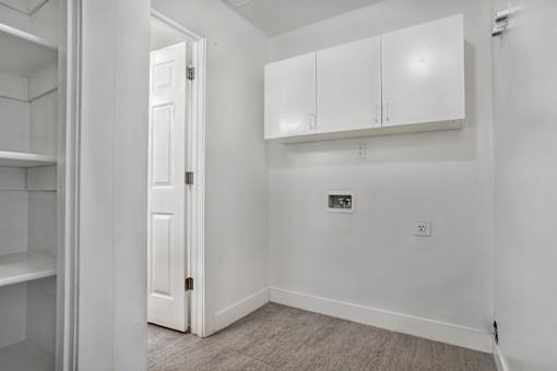 A white door is open to a room with white walls and a white cabinet.