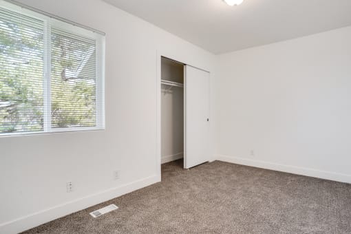 an empty bedroom with a large window and a closet