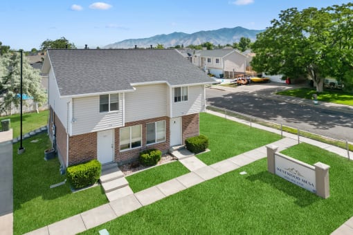 an aerial view of a white and brick house with a yard and grass