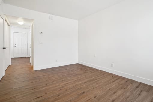 an empty living room with white walls and wood flooring