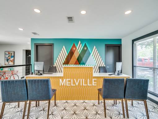 A reception area with a yellow desk and blue chairs.