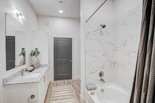 Modern bathroom with marble tile shower at The Mill Old Town Apartments, Lewisville