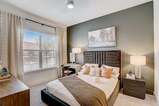 Bedroom with tufted headboard and window views at The Mill Old Town Apartments, Texas, 75057