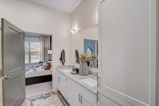 Bathroom vanity with dual sinks and granite countertop at The Mill Old Town Apartments, Lewisville, TX 75057