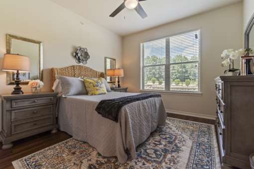 Spacious bedroom at Auberge of Tyler apartments in Tyler TX with ceiling fan and natural light.