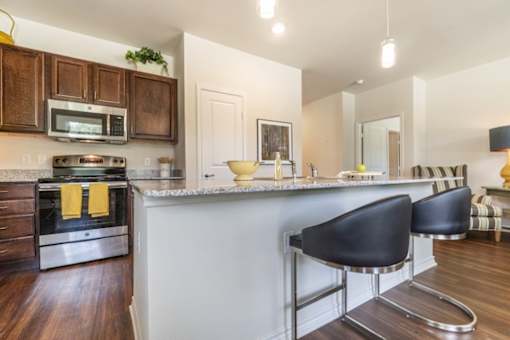 Kitchen with granite countertops and breakfast bar at Auberge of Tyler apartments in Tyler TX.
