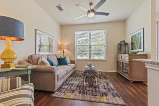 Bright living room with ceiling fan at Auberge of Tyler apartments in Tyler TX.