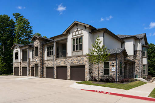 Apartment building with attached garages and landscaped grounds at Auberge of Tyler.