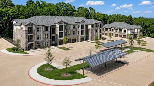 Apartment buildings and covered resident parking at Auberge of Tyler.