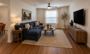 Stylish living room with comfortable seating, entertainment area, and wood-style flooring at Auberge of Tyler.