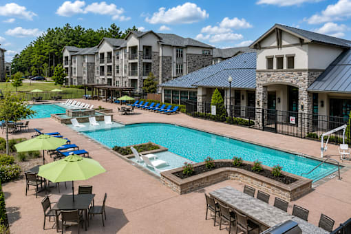 Resort-style swimming pool with lounge chairs surrounded by apartment buildings at Auberge of Tyler.