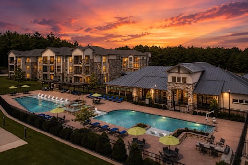 Resort-style pool at sunset with beautifully lit apartment homes at Auberge of Tyler.