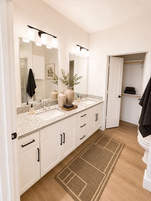 pacious primary bathroom featuring dual sinks, granite countertops and modern finishes.