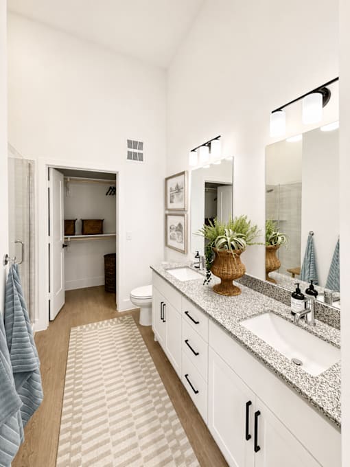 Spacious primary bathroom featuring dual sinks, granite countertops and modern finishes.