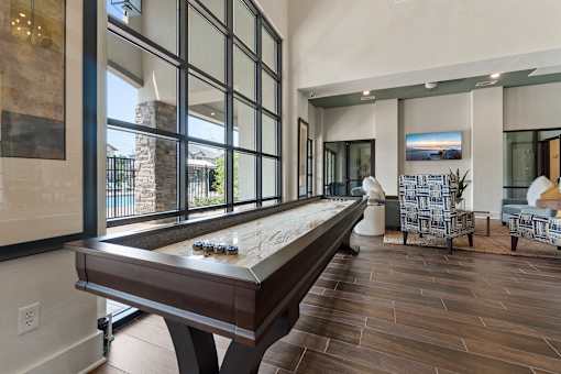 A pool table is in the middle of a room with a view of the backyard.