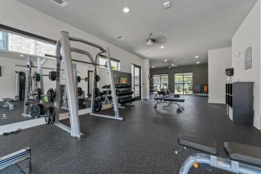A gym with a variety of equipment including weights and a bench.