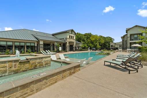 Swimming pool and stone feature wall at Auberge of Tyler apartments in Tyler TX.