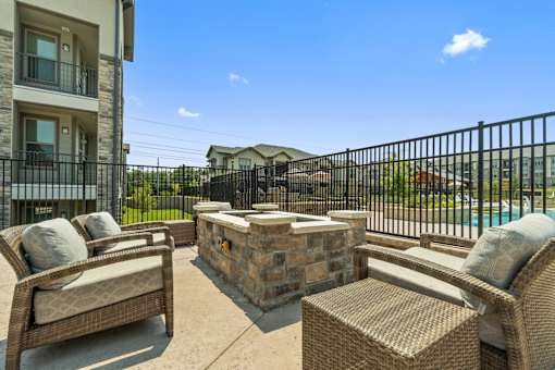 Outdoor patio with stone fireplace at Auberge of Tyler apartments in Tyler TX.