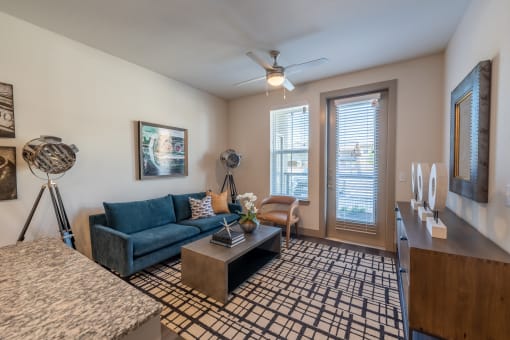 a living room with a blue couch and a brown coffee table at One Preston Station, Celina