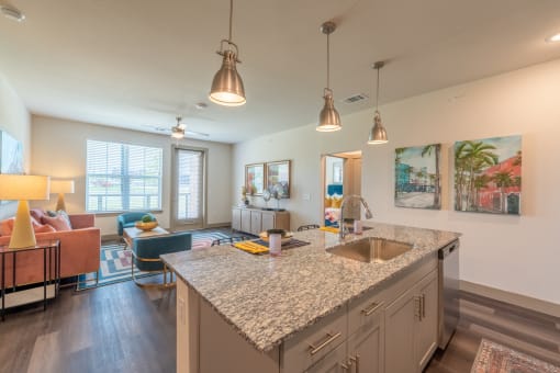 a kitchen with an island and a living room in the background at One Preston Station, Texas, 75009