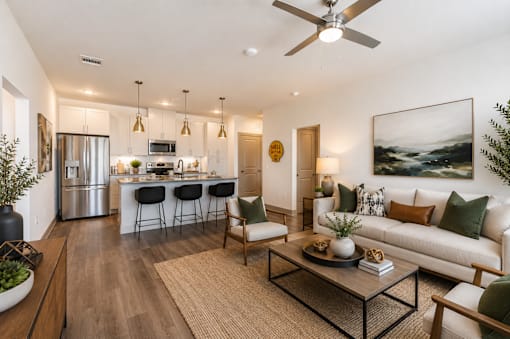 Open-concept apartment living room with a modern kitchen, large island, stainless steel appliances, and luxury finishes at One Preston Station in Celina, TX.