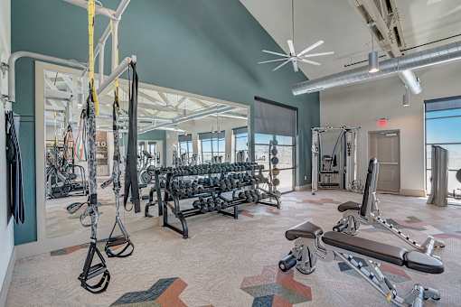Modern apartment fitness center with cardio equipment and weights.