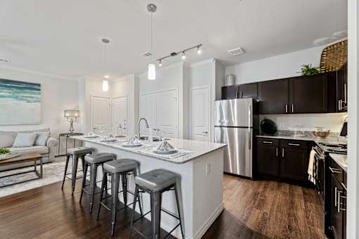 Modern kitchen with breakfast bar and granite countertops at Auberge of Burleson apartments in Burleson TX.