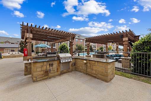 Outdoor grilling stations by the resort-style pool at Auberge of Burleson apartments in Burleson TX.