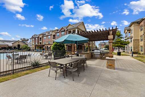 Poolside patio seating area at Auberge of Burleson apartments in Burleson TX.