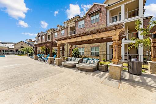 A sunny day at a residential complex with a pool and a covered patio area.