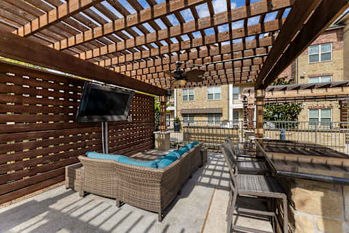 Outdoor lounge patio with seating and television at Auberge of Burleson apartments in Burleson TX.