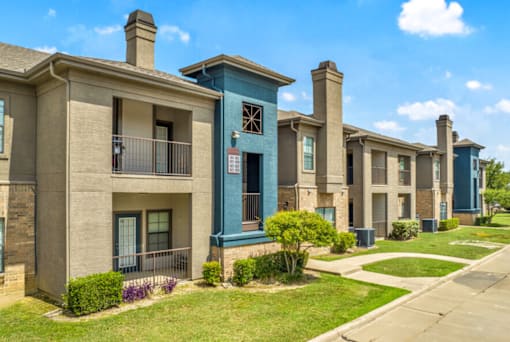 a row of townhomes with balconies and grass and a sidewalk