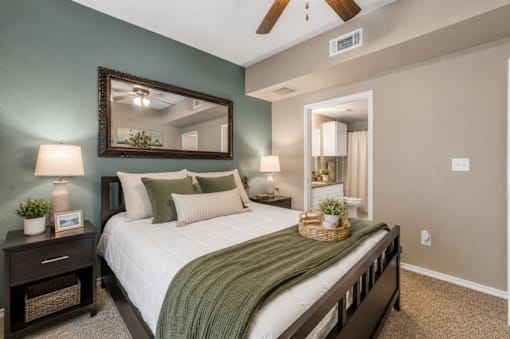 A bedroom with a bed, nightstands, and a mirror.