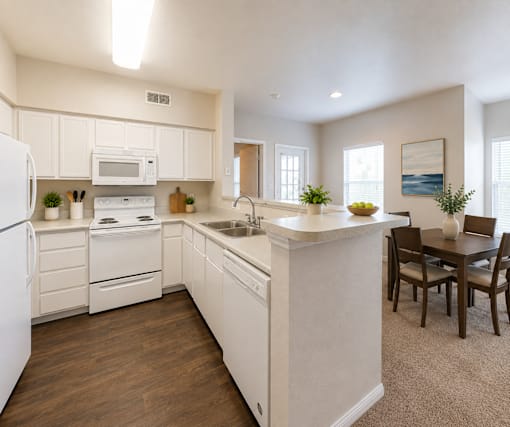 A kitchen with white appliances and wooden floors.