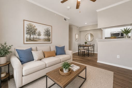 A living room with a white couch, a painting on the wall, and a ceiling fan.