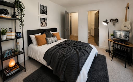 A bedroom with a large bed and a guitar on the wall.