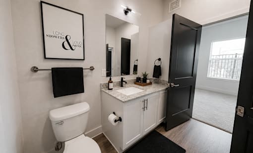 A bathroom with a toilet, sink, and a mirror.