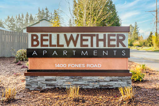A sign for Bellwether Apartments stands in front of a wooded area.