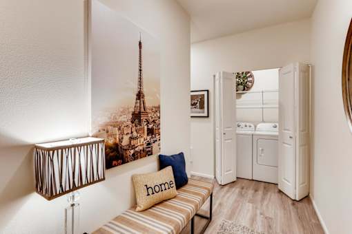 A room with a picture of the Eiffel Tower on the wall and a couch with a blue pillow that says home.