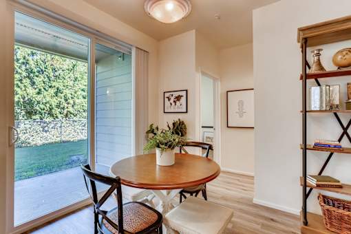A dining room with a table and chairs and a sliding glass door.
