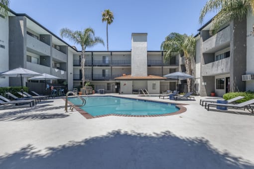 a swimming pool with lounge chairs and umbrellas in front of a building