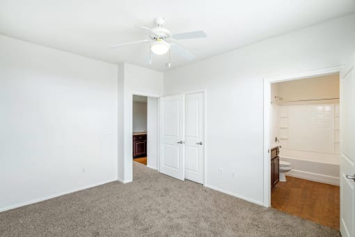 2 BR Apartments in North Las Vegas NV - Sonata - Spacious Carpeted Bedroom With White Ceiling Fan And Light, Double Door Closet Storage, And Open Entry To Nearby Bathroom And Vanity Area
