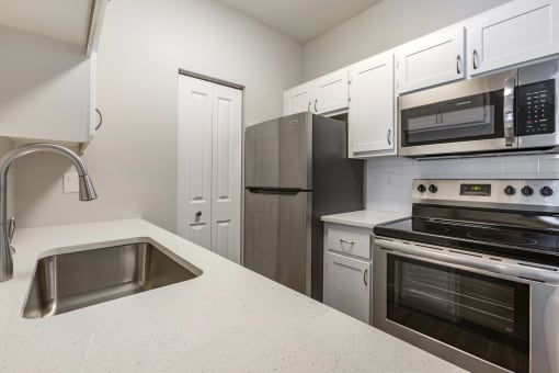 Experience culinary bliss in our sleek kitchen adorned with pristine white cabinets and modern stainless steel appliances at Boulders at Lookout Mountain Apartment Homes, Phoenix, AZ
